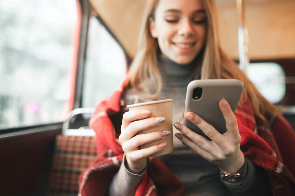 Femme qui utilise un téléphone intelligent et tient un café