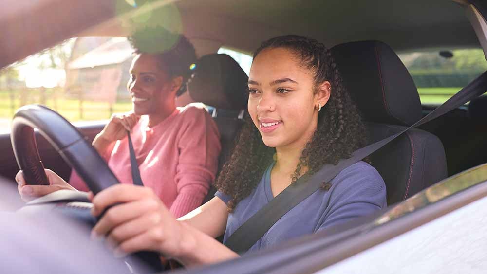 Teenage girl learning to drive with her mother