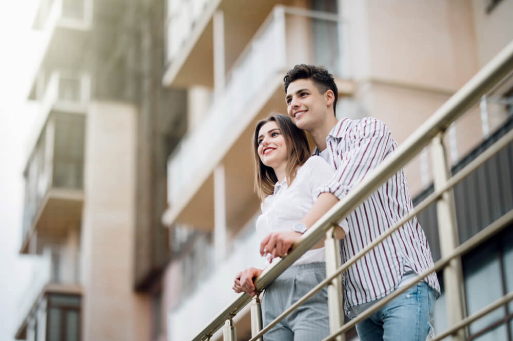 Jeune couple assis au balcon d'une copropriété