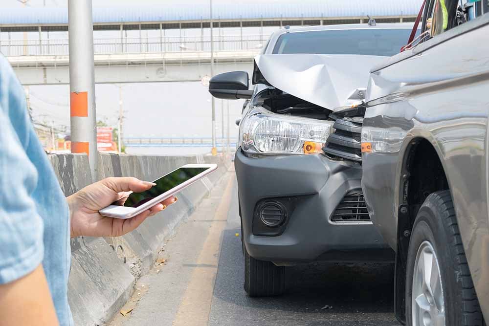 Une femme documente un accident de voiture avec son t├⌐l├⌐phone intelligent