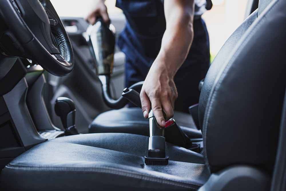 Person vacuuming the inside of a car