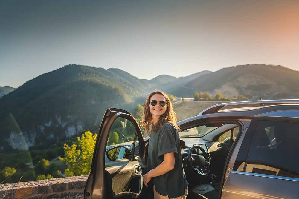 Femme debout près d'une porte de voiture ouverte