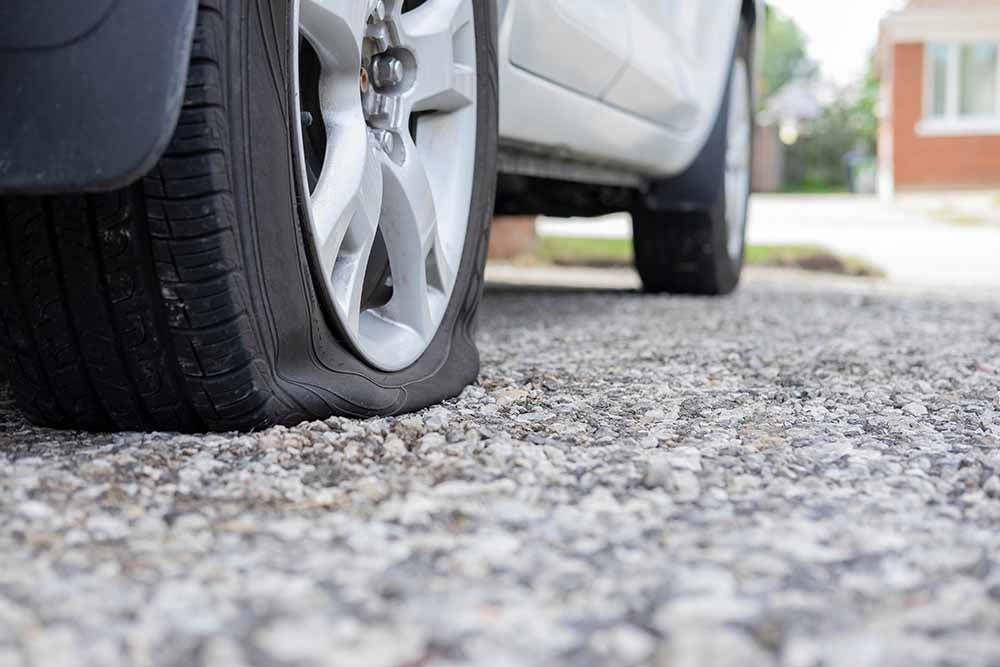 Véhicule avec une crevaison stationné dans une entrée de garage