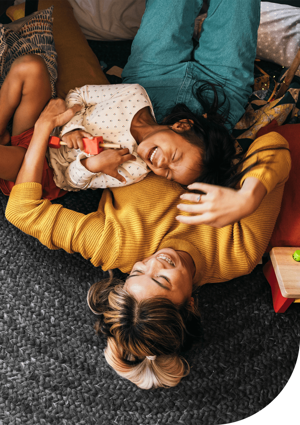 Une mère et son enfant allongés sur un tapis, riant et jouant ensemble à la maison.