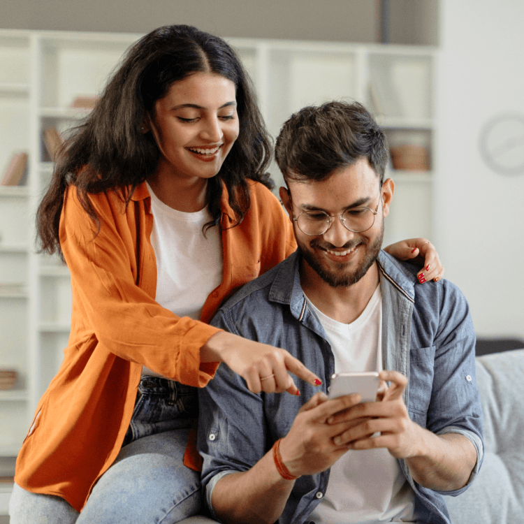 Un couple est heureux d’utiliser leur téléphone intelligent pour obtenir une soumission d’assurance habitation en ligne.